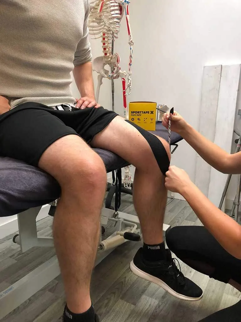 Kinesiology taping being applied to the clients knee.
